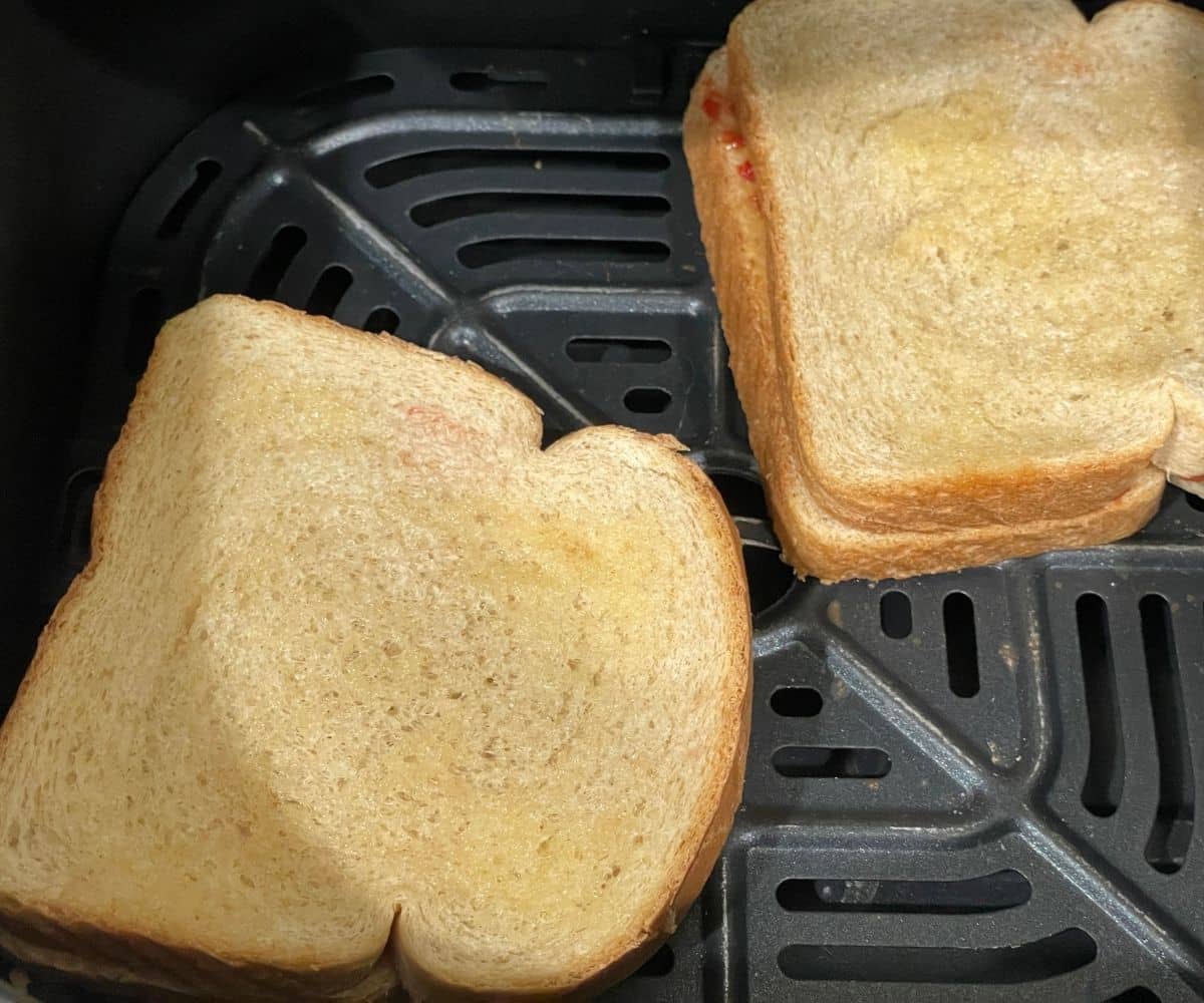 The air fryer basket has peanut butter sandwich.