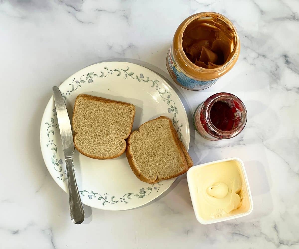 A table is covered with peanut butter jelly sandwich ingredients.
