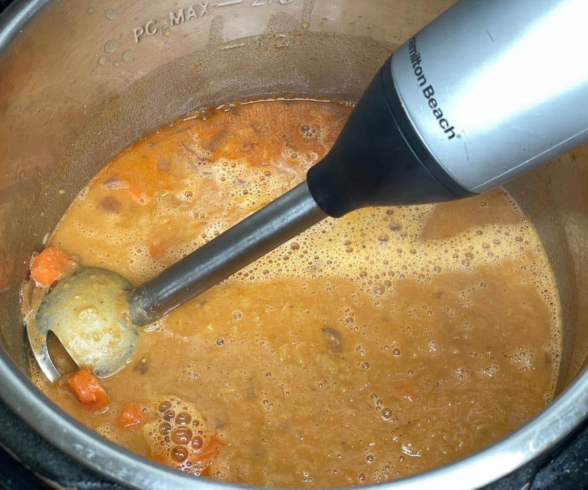 Blending a pot is with lentil soup using a hand blender.