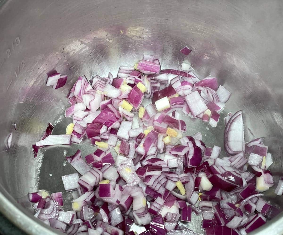 An instant pot has chopped onions on saute mode.