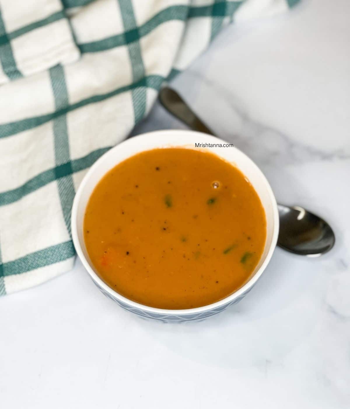 A bowl of yellow Lentil soup is on the table.