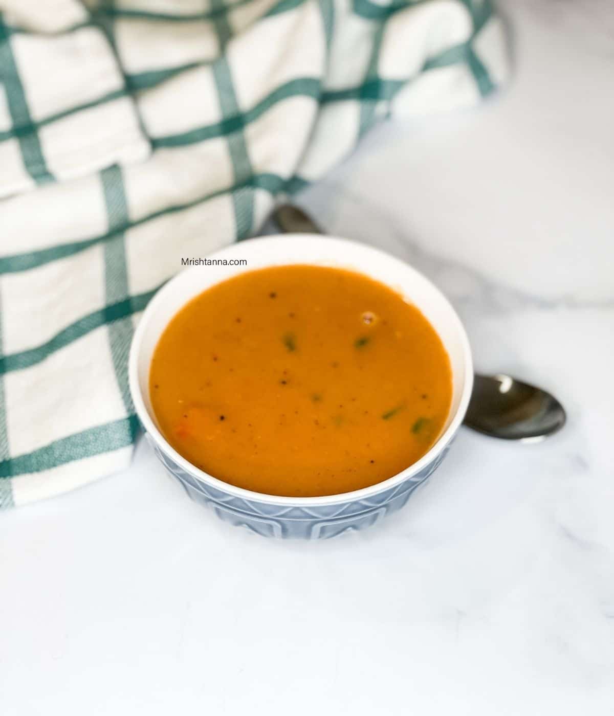 A bowl of yellow Lentil soup is on the surface.