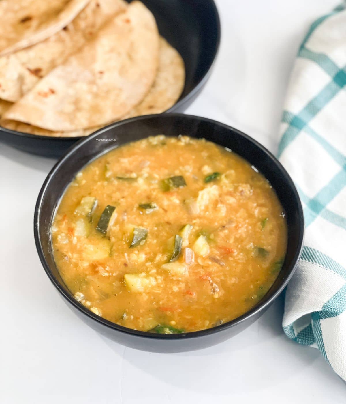 A bowl of zucchini dal is on the table.