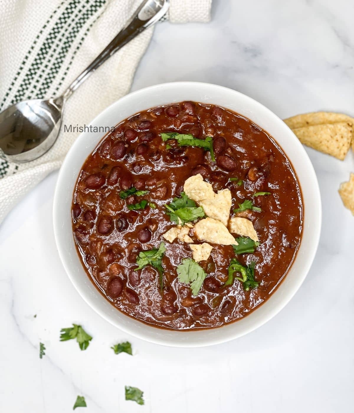 a bowl of black bean chili is on the table.