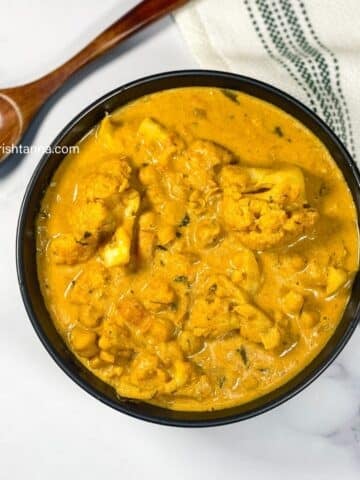 A bowl of vegan gobi tikka masala curry is on the table.